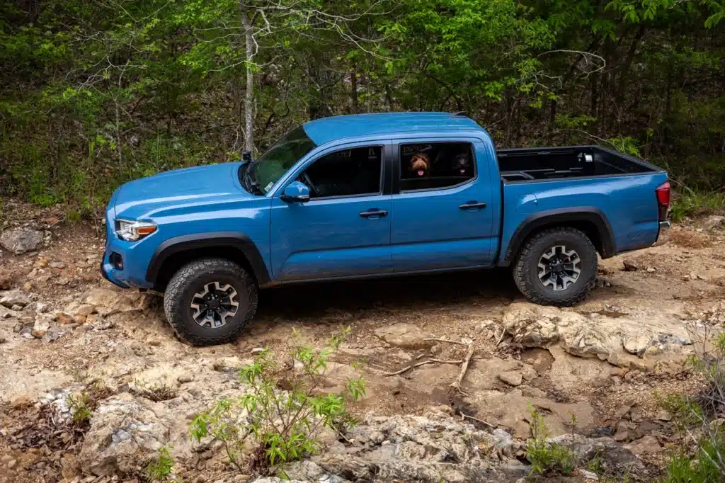 Blue Toyota Tacoma driving on dirt road